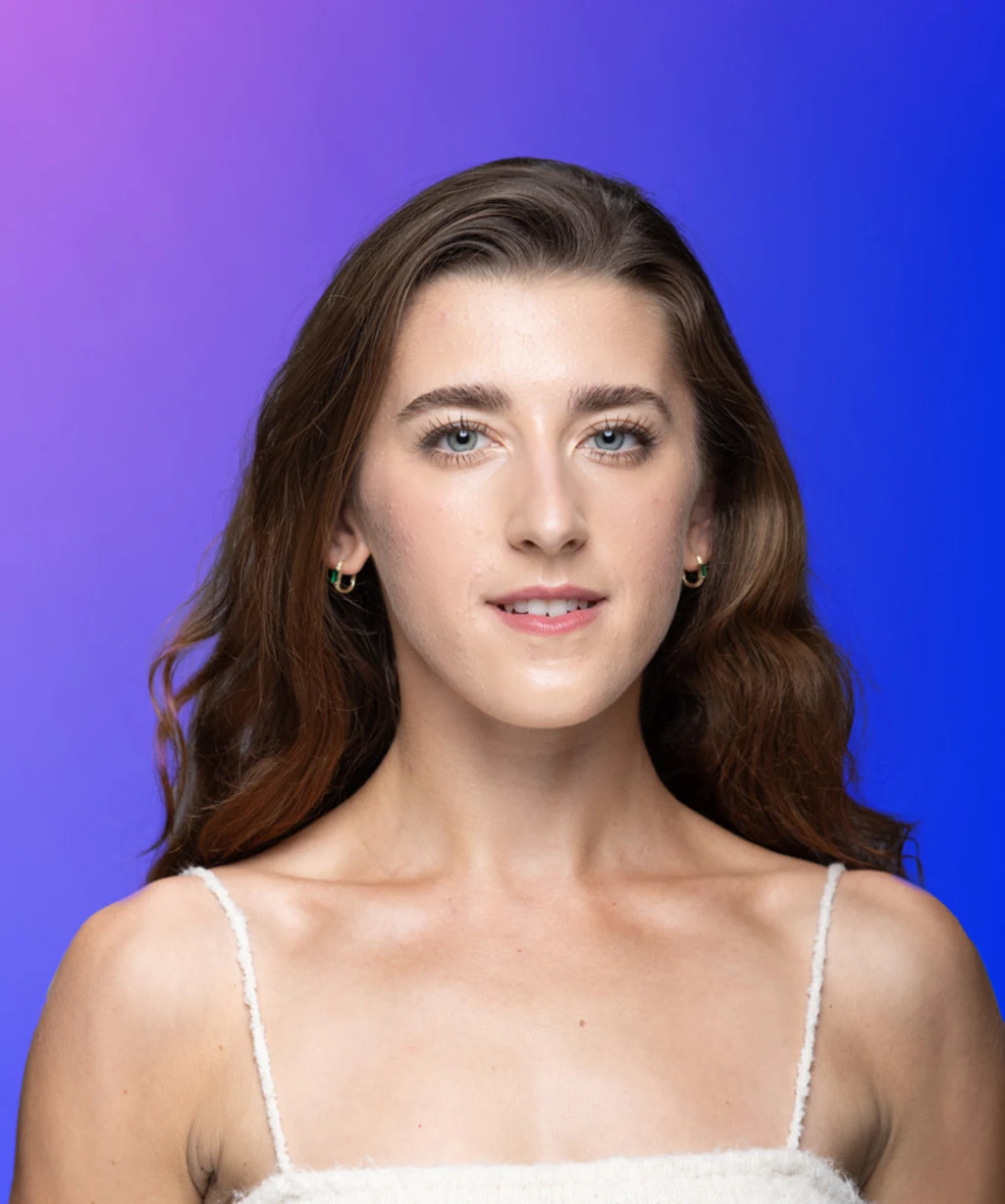 Picture of a young brunette woman with bare shoulders and blue eyes wearing a white top and hoop earrings