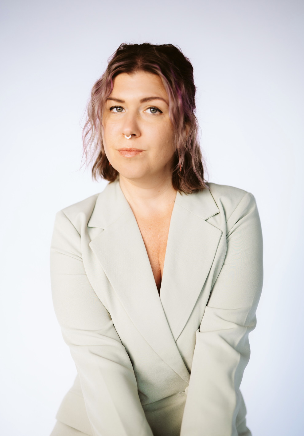 Image of woman in a white blazer with crimped strawberry blonde hair looking at the camera